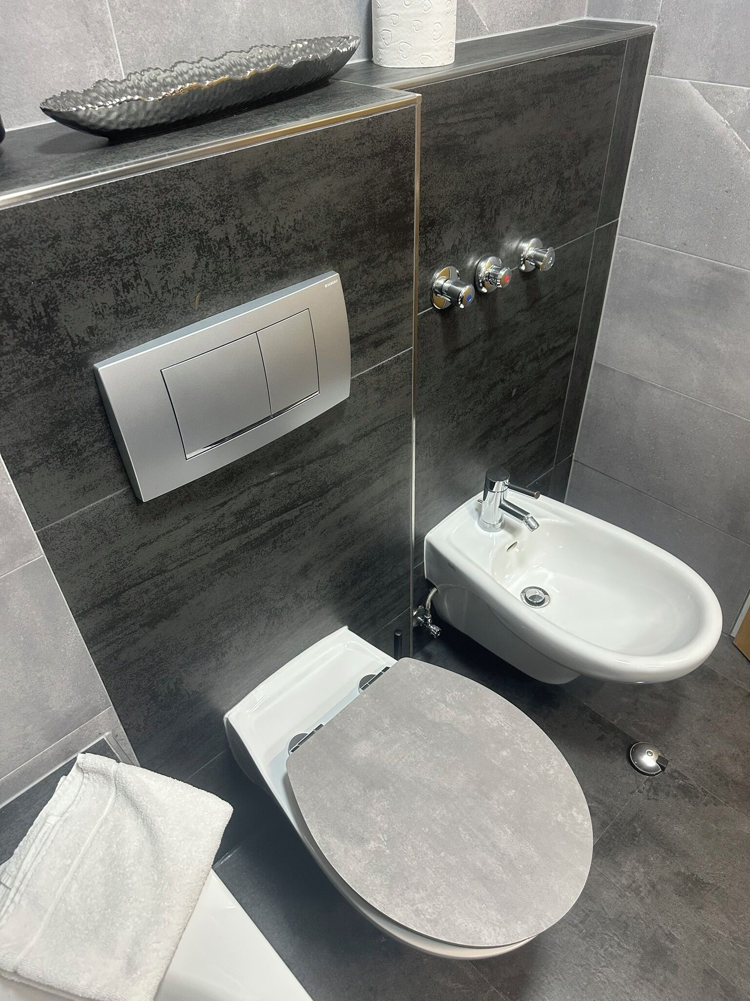 Ein modernes Badezimmer mit Toilette, Bidet und einem großen Spiegel.