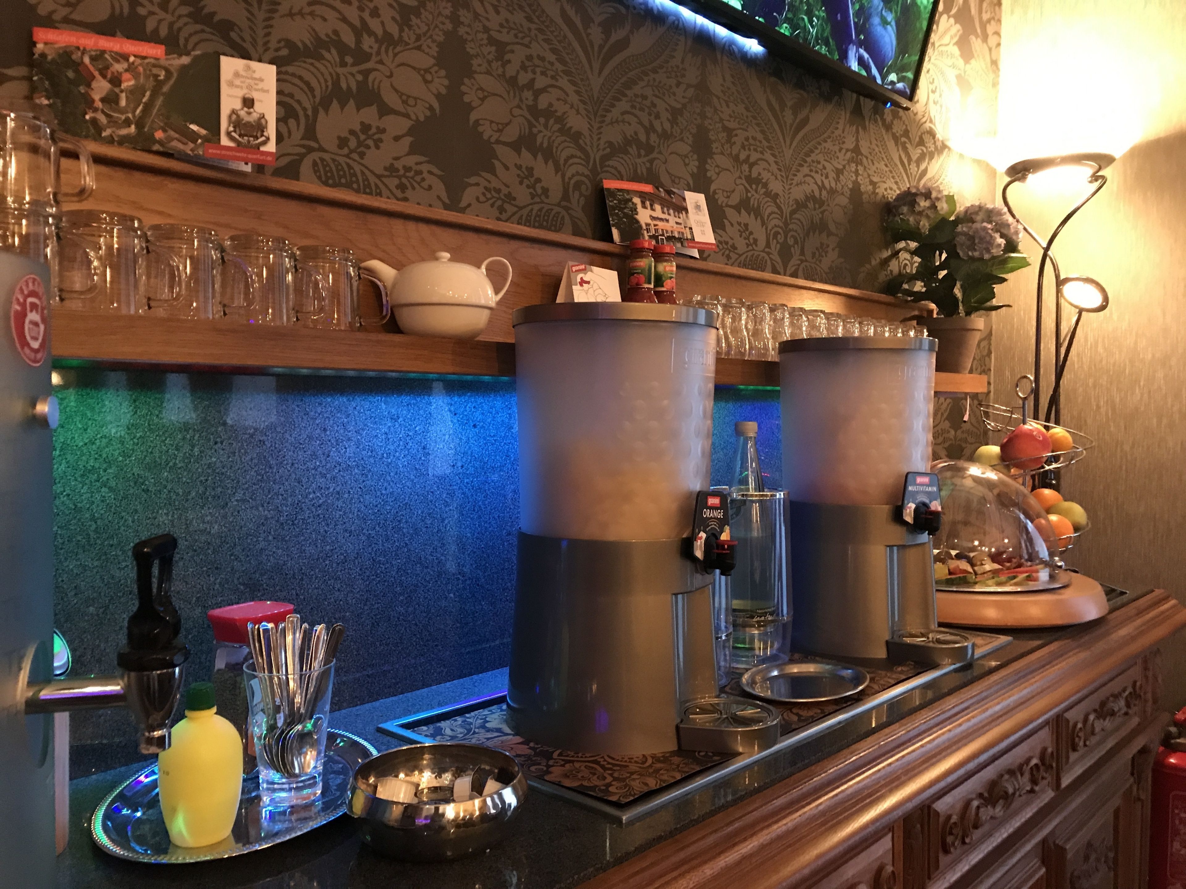 A bar area with two large dispensers, a tray with condiments, and a fruit display.