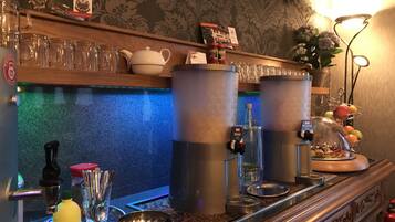 A bar area with two large dispensers, a tray with condiments, and a fruit display.