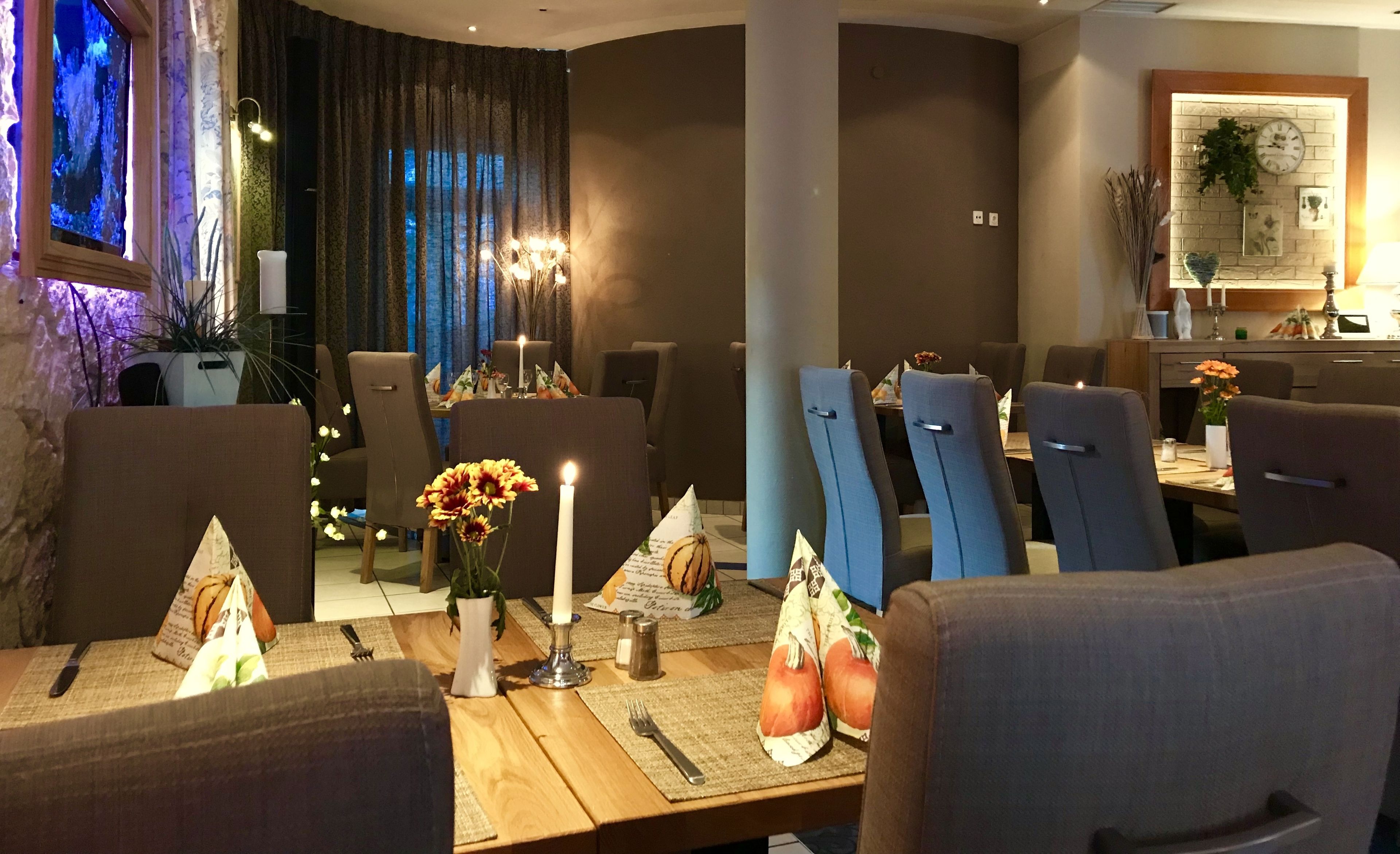 A dining area with a wooden table, chairs, candles, and a vase with flowers.