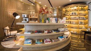 A modern, well-lit reading area with a curved bookshelf, a comfortable chair, and a decorative vase with flowers.