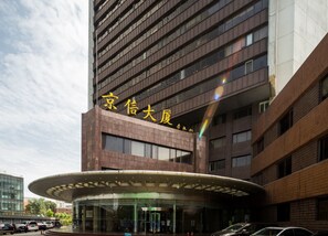 Ein modernes Gebäude mit einem geschwungenen Eingang und einem Schild mit chinesischen Schriftzeichen.