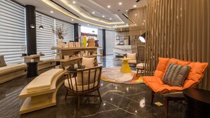 A modern interior with a curved sofa, a wooden chair, a small table, and a decorative vase.