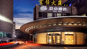 A modern hotel with a curved entrance and a prominent sign displaying the name and logo.
