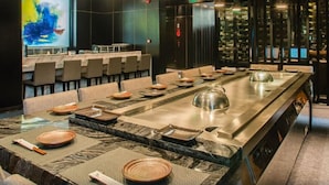 Un restaurante moderno con una larga mesa común, asientos individuales y un manantial termal central.