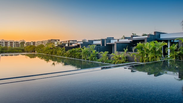 Zona residencial moderna con una amplia piscina cristalina que refleja los edificios y el cielo.