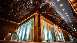 Un escenario con cortinas decorativas y un atril para micrófono, sugiriendo un ambiente para un evento formal.