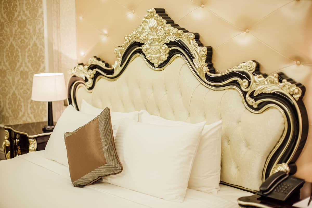 A bed with a tufted headboard, a lamp, and a telephone on a bedside table.