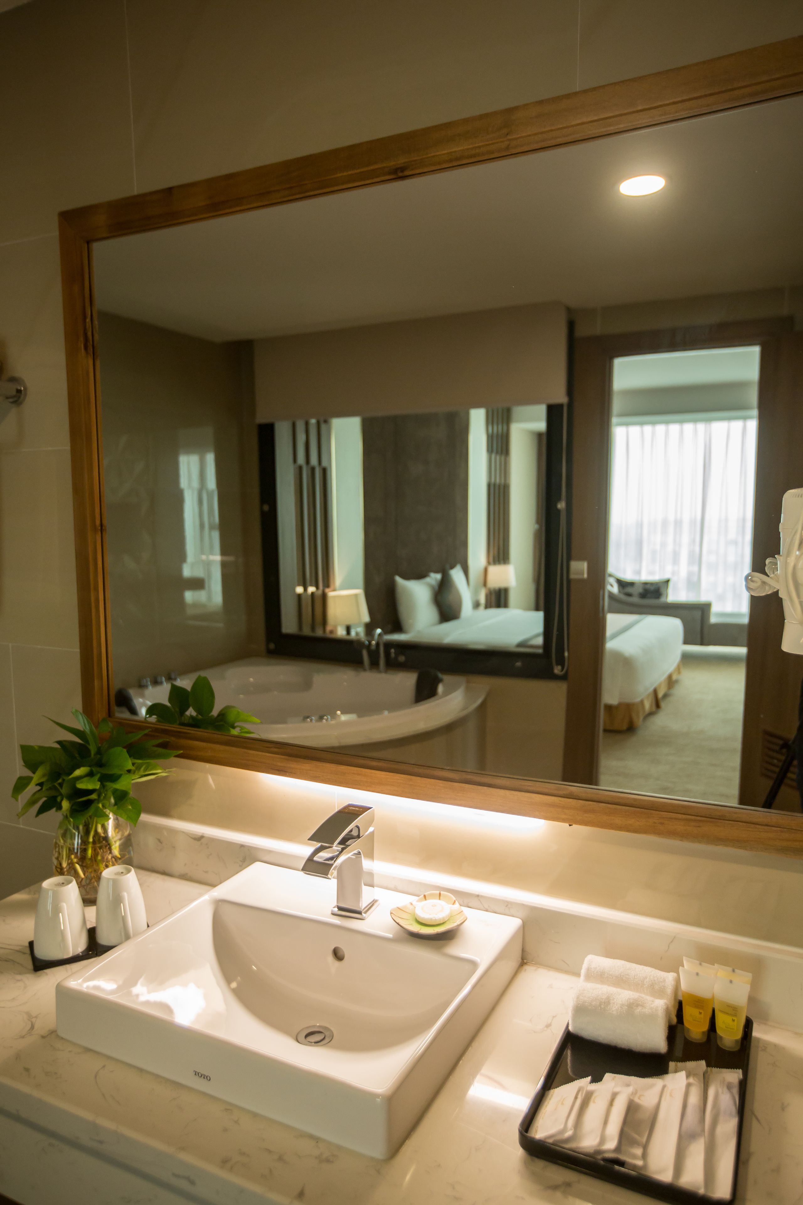 A bathroom with a large mirror, a sink, and a bathtub.