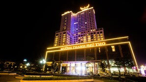 Um hotel com vários andares, sinalização iluminada e entrada bem iluminada.