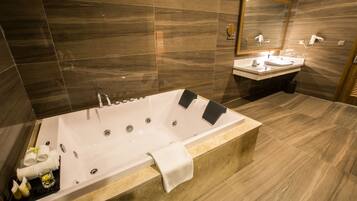 Un baño moderno con una bañera grande, un tocador con espejo y un inodoro.