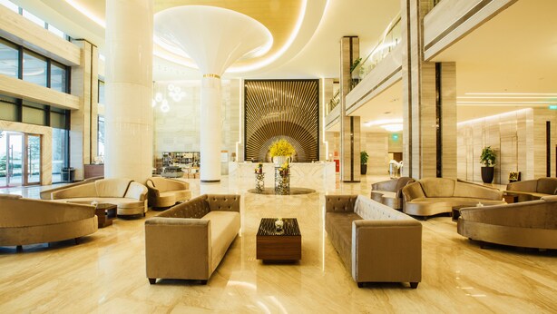 Um hall espaçoso com um balcão de recepção central, diversas áreas de estar e um design arquitetônico moderno.