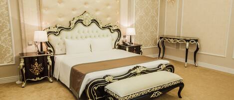 A luxurious bedroom with a tufted headboard, a large bed, two bedside tables, a nightstand, a bench, and a small table with a lamp.