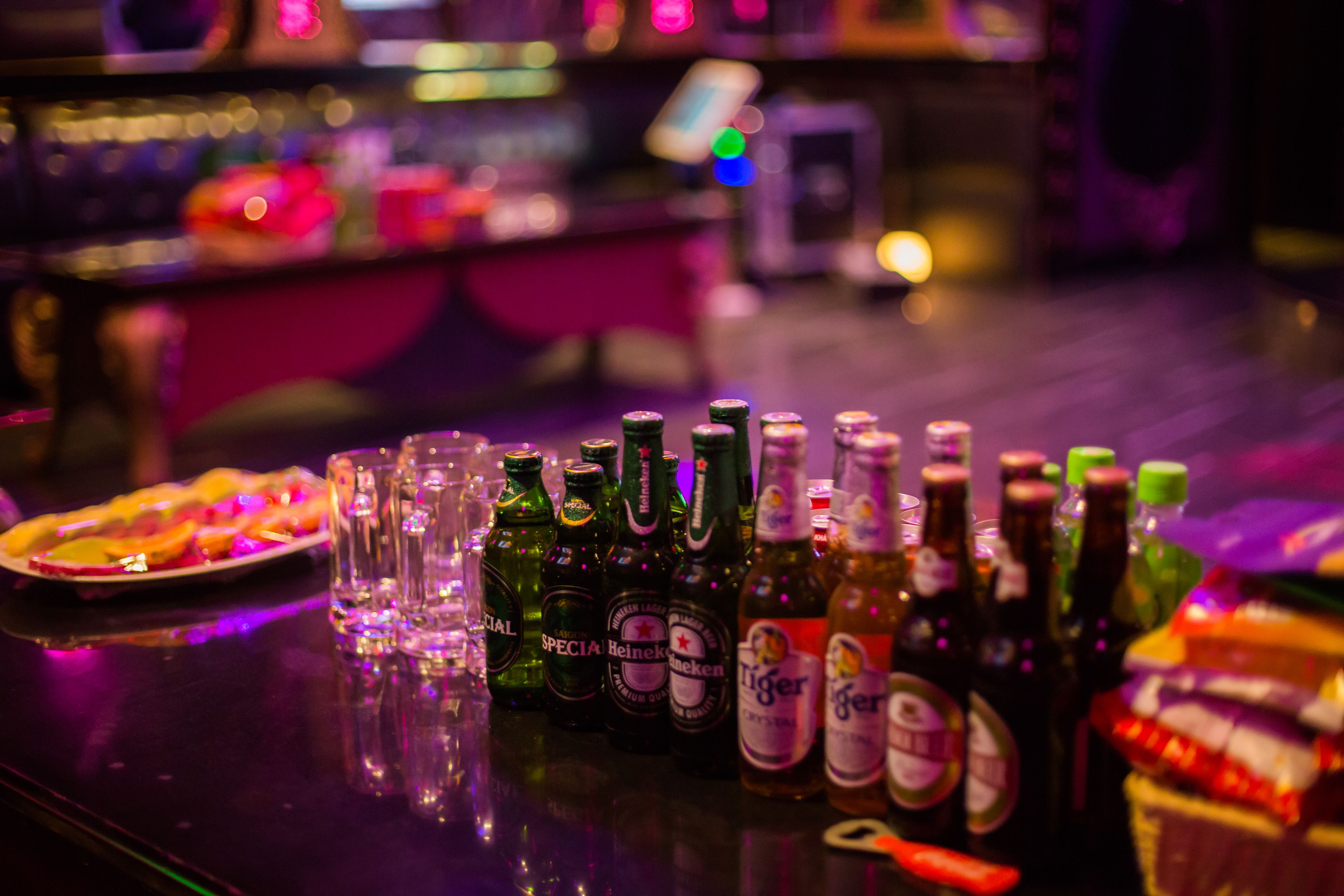 A bar counter with various bottles of beer and glasses.