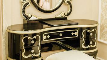 A black vanity with a mirror, a drawer, and a cushioned stool.