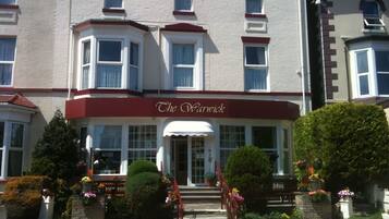 Um edifício com uma placa na entrada que diz "The Warwick".