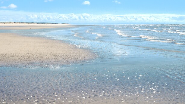 A beach with gentle waves, a sandy shore, and a clear sky. - The Warwick Southport (Southport)