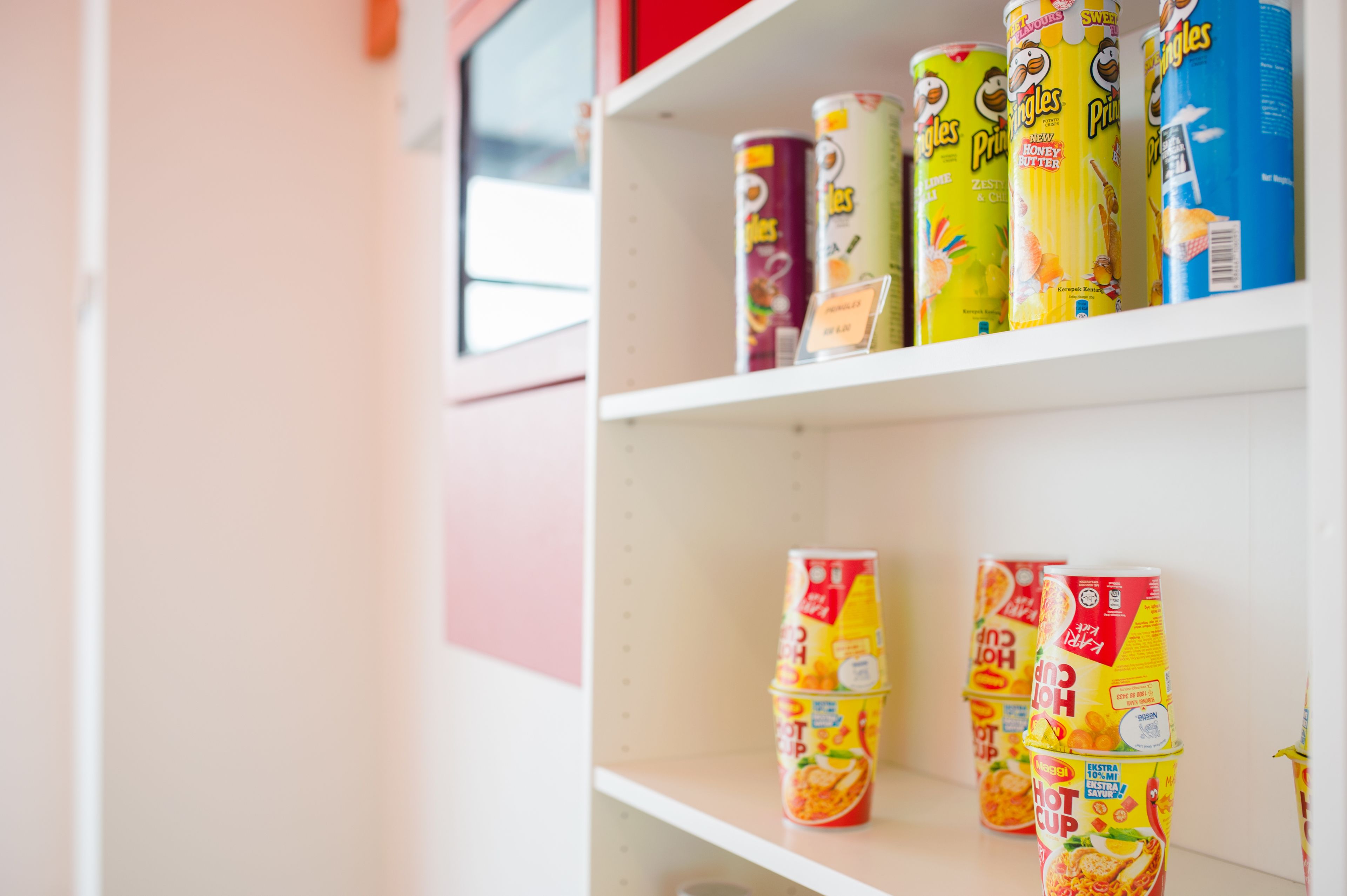 A shelf with various canned beverages, including brands like Pringles and hot cup drinks.