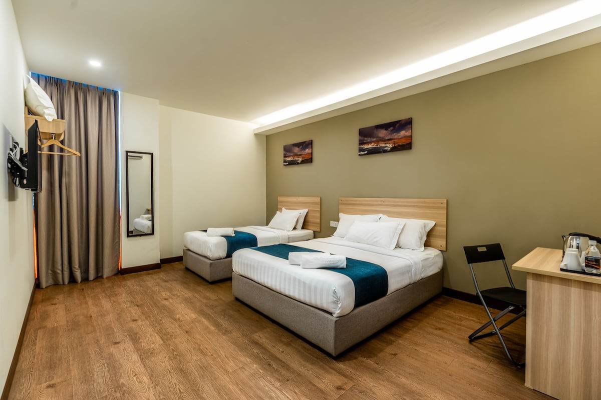 A hotel room with two beds, a desk, a chair, a mirror, and artwork on the wall.