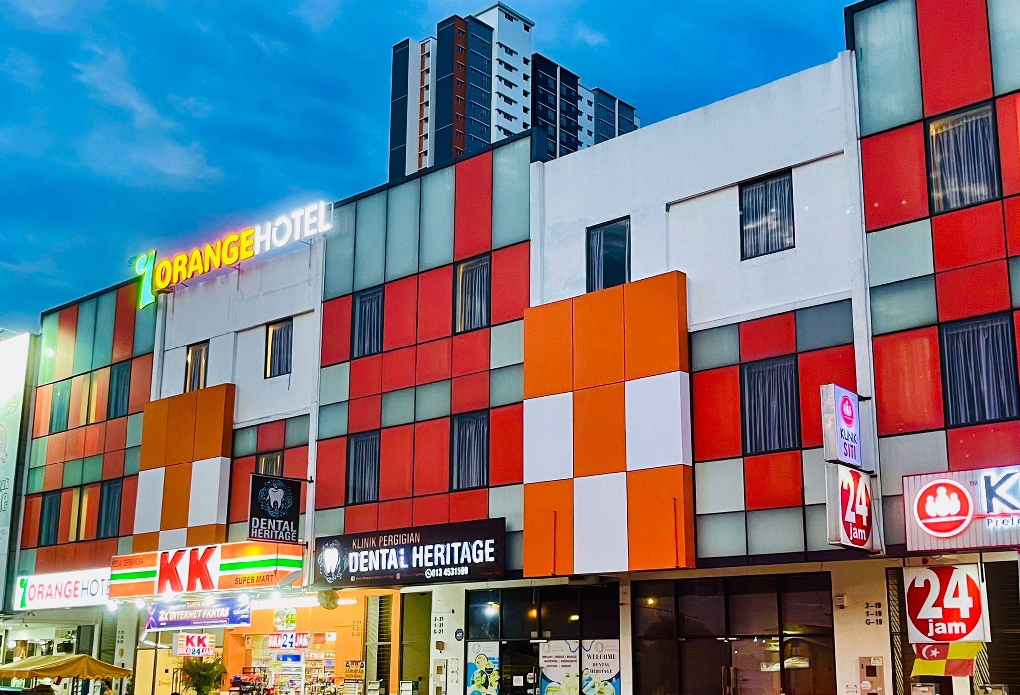A multi-story building with a colorful facade, featuring a hotel named "Orange Hotel" and a dental clinic.