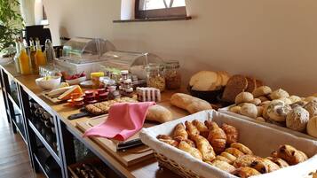 A breakfast buffet with various breads, pastries, and condiments.