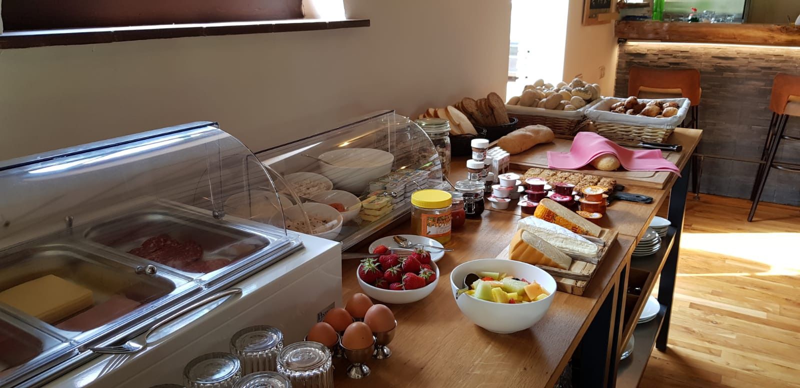 Un bufé con diversos alimentos, entre ellos carnes, quesos, panes y frutas.