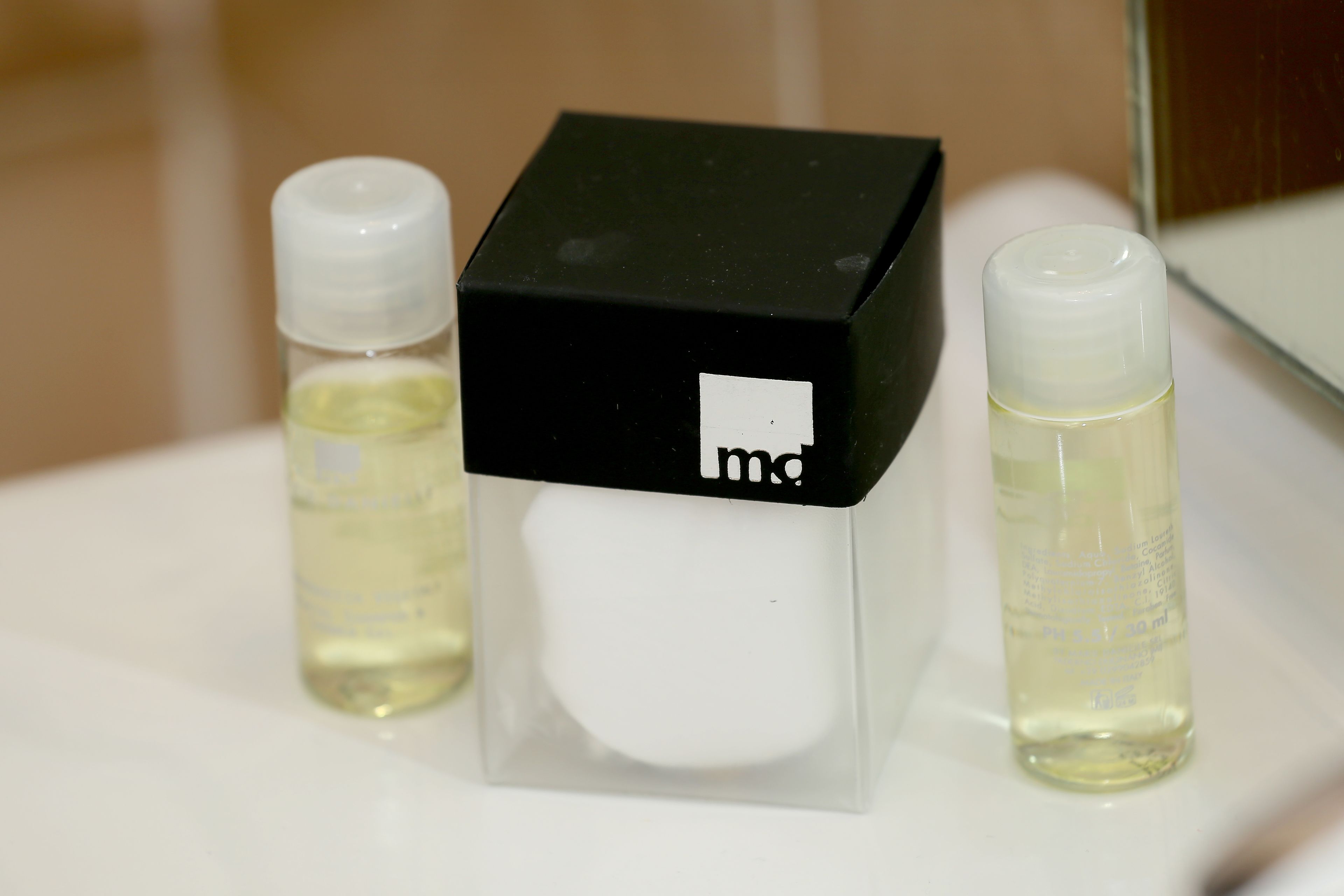 A bathroom with a white sink, a black and white box, and two bottles of liquid.