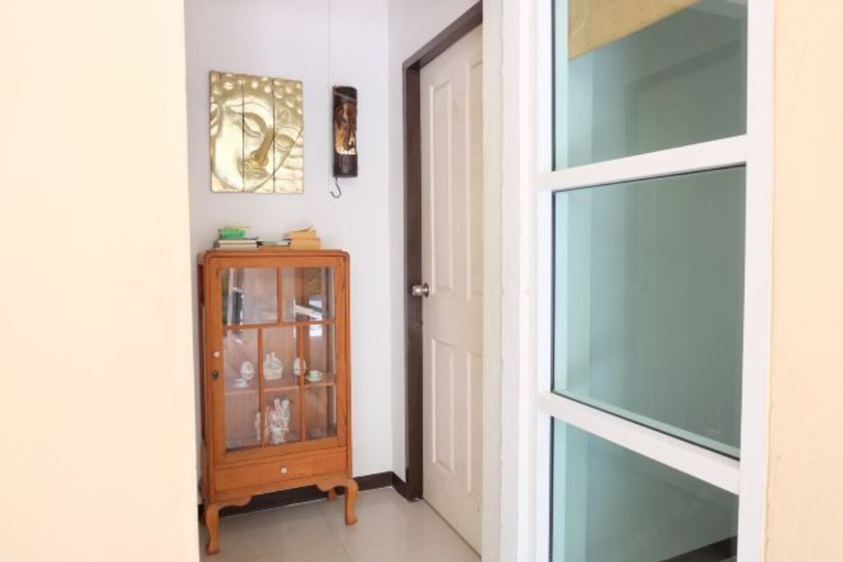 A hallway with a wooden cabinet, a white door, and a glass door.