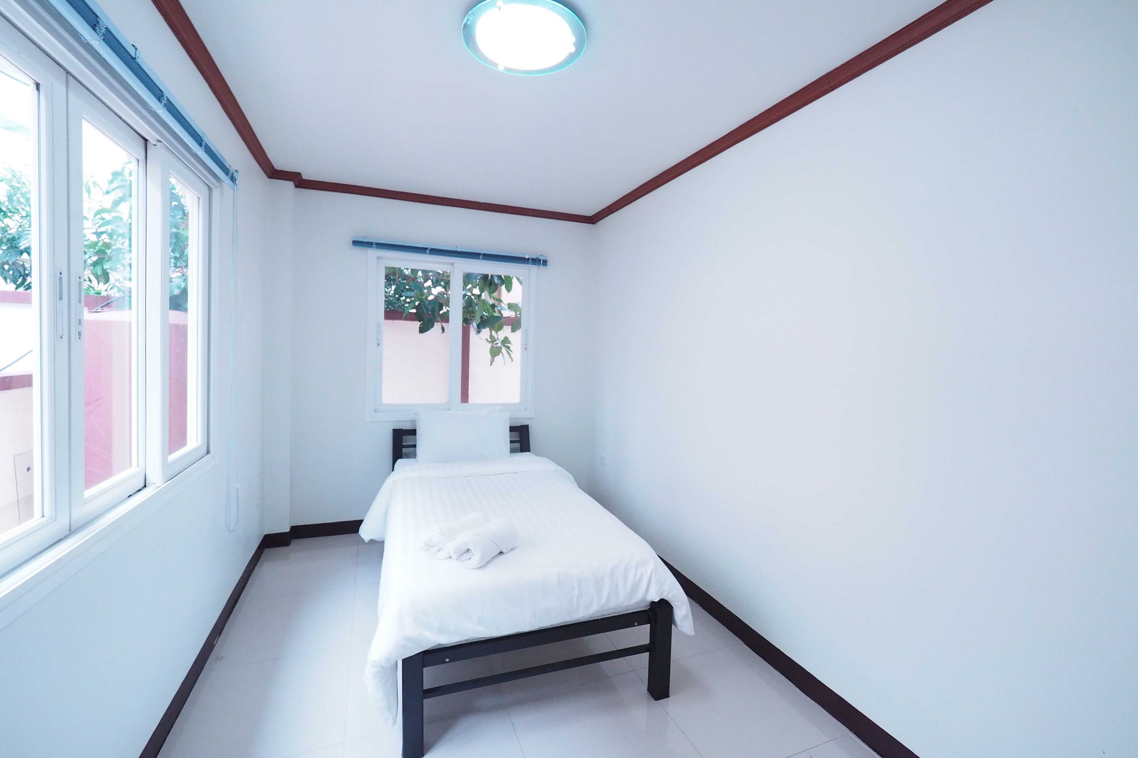 Una habitación pequeña y limpia con una cama individual, una ventana y una lámpara en el techo.