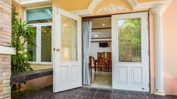 Un vestíbulo con puerta de cristal, un banco y una zona de comedor con sillas y una mesa.