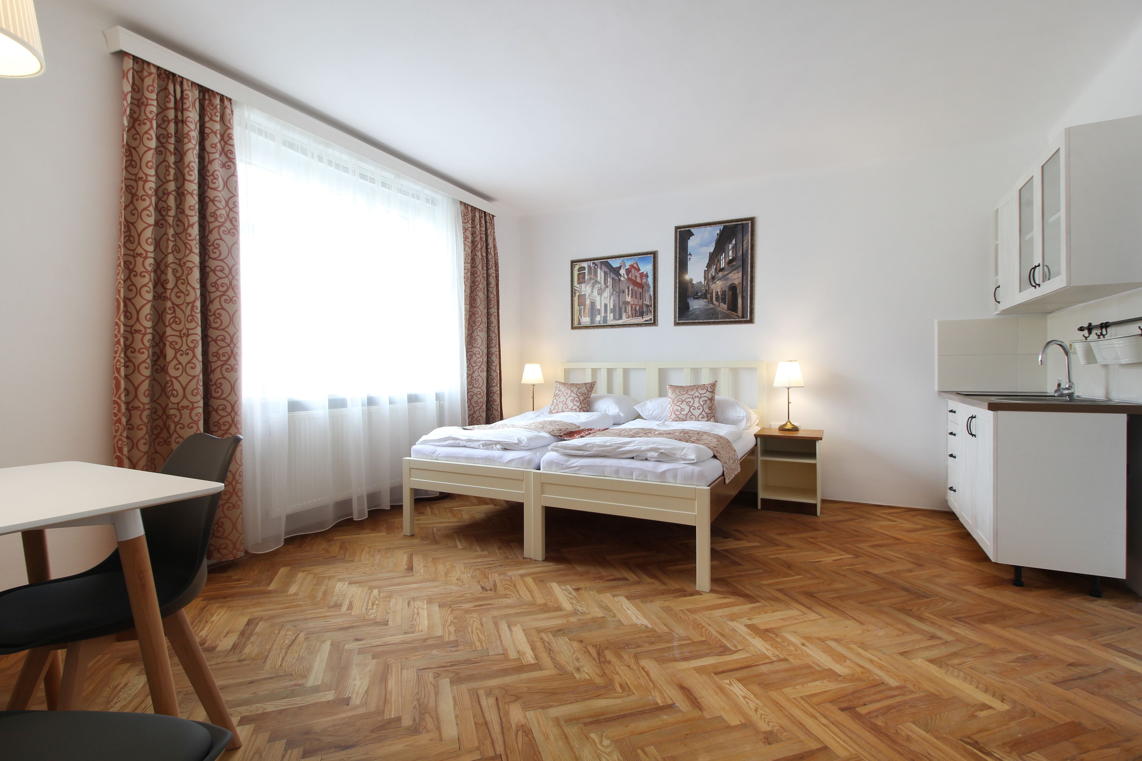 Ein Schlafzimmer mit Bett, Nachttischen, einem Schreibtisch und einer Küchenzeile.