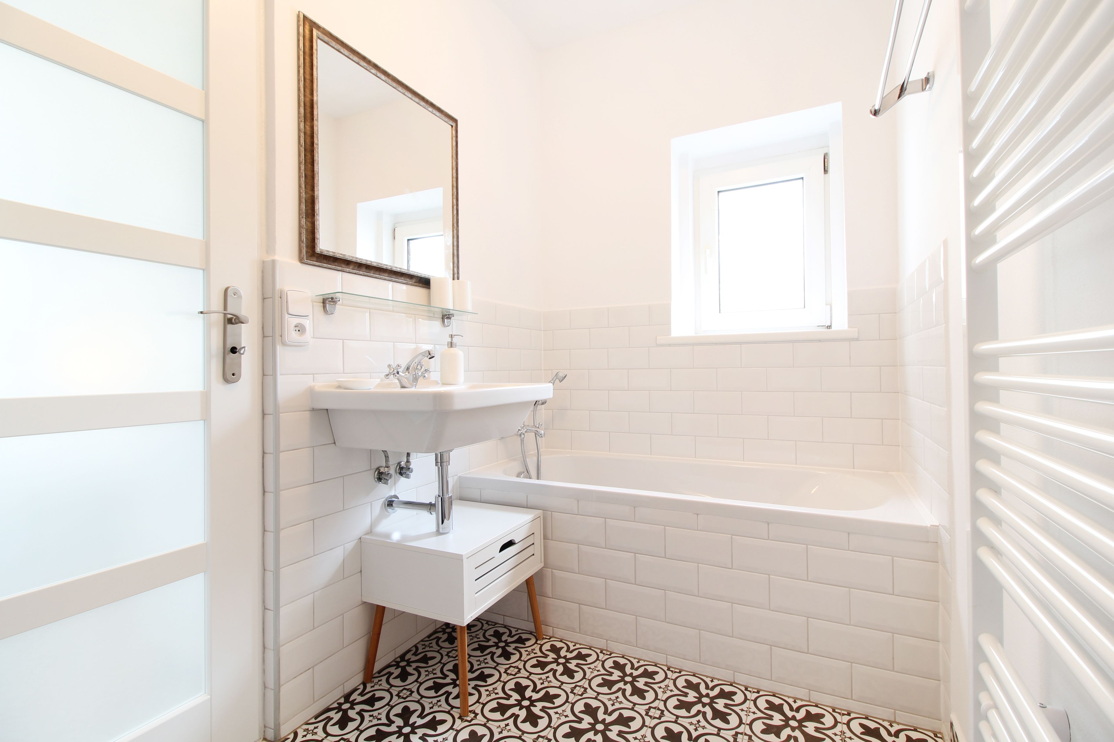Un baño con lavamanos blanco, espejo y bañera.