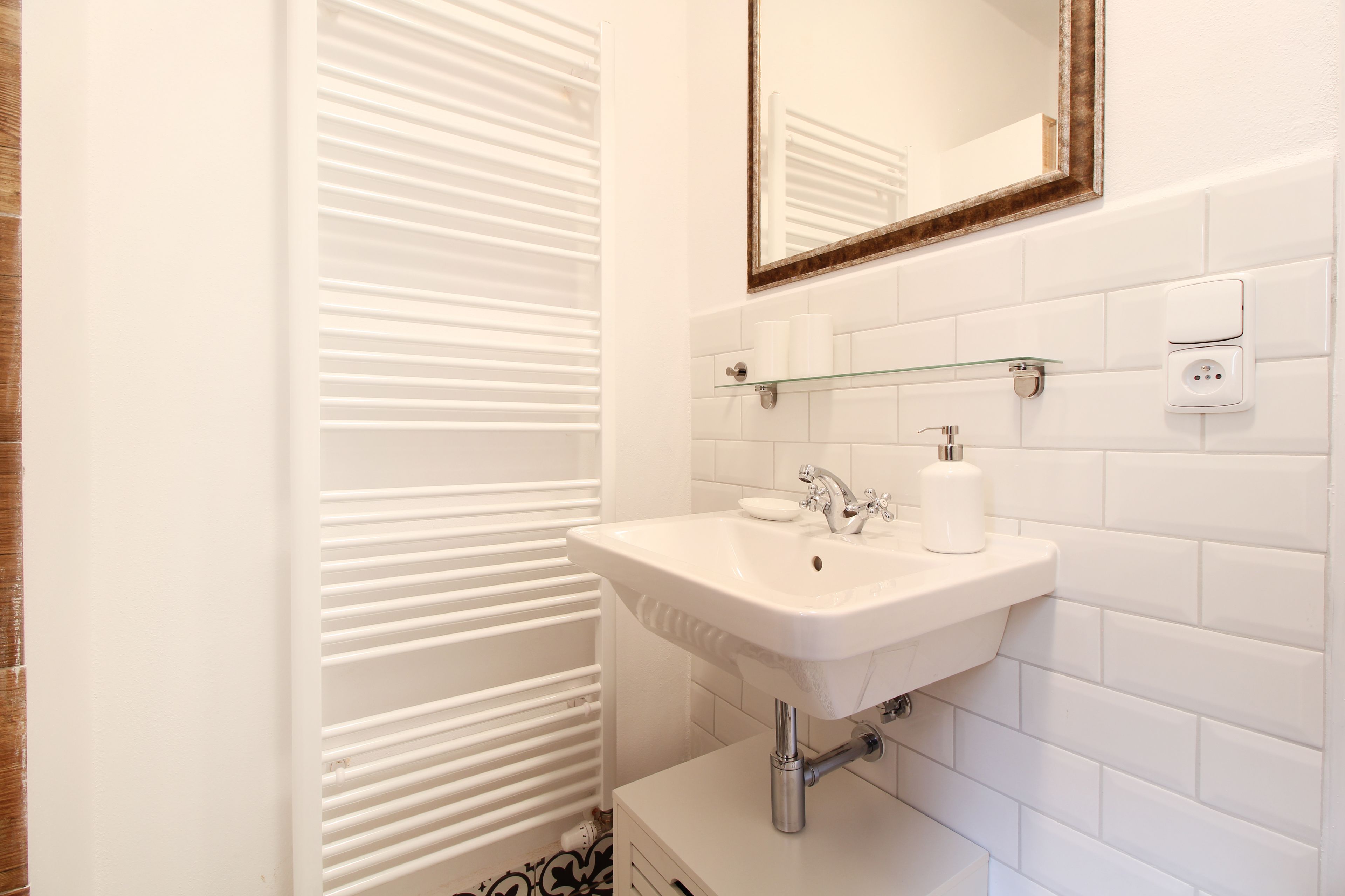 Une salle de bain avec un lavabo blanc, un miroir et un porte-serviettes.