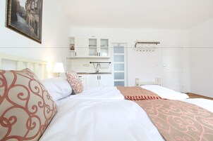 Una habitación de hotel con cama, mesita de noche, armario y vista a la calle.