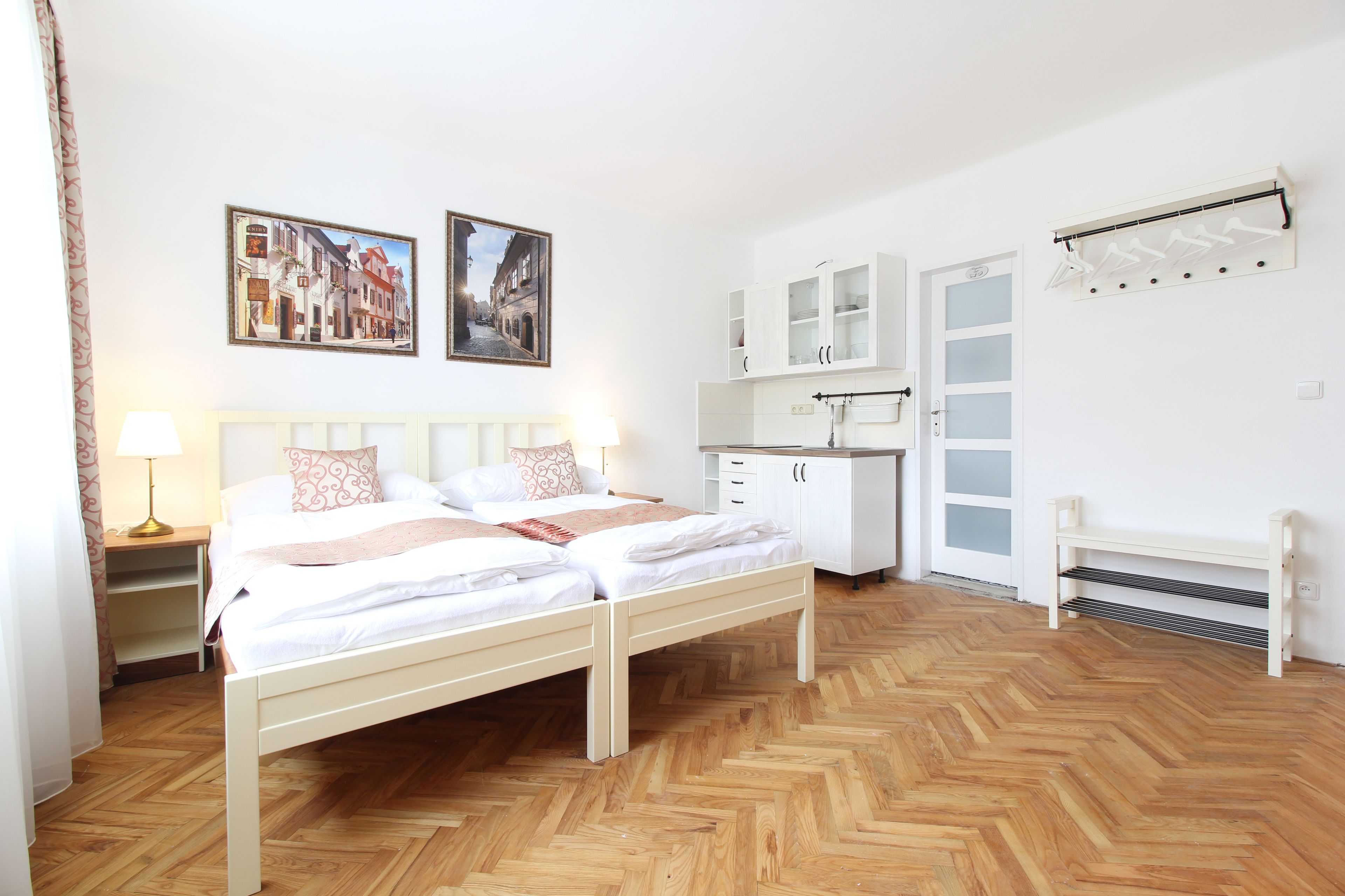 A bedroom with a double bed, a nightstand, a dresser, a wardrobe, and a bench.