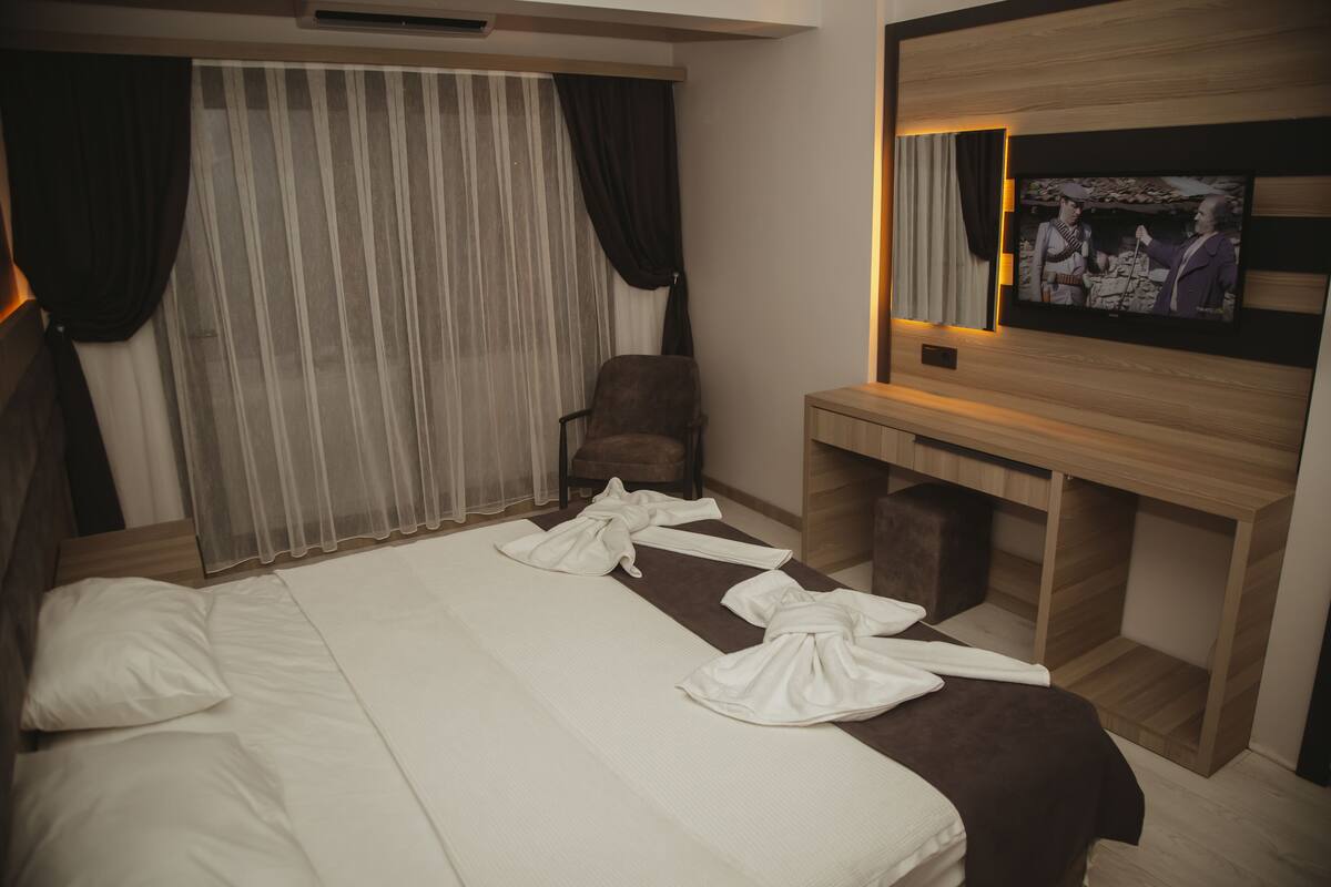 A hotel room with a bed, a chair, a TV, and a desk.