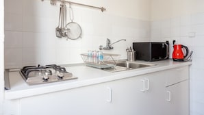 Een moderne keuken met witte kasten, een gasfornuis, een spoelbak, een waterkoker en een magnetron.