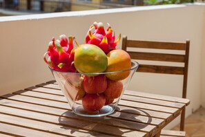 A glass bowl filled with dragon fruit, mango, and peaches on a wooden table.