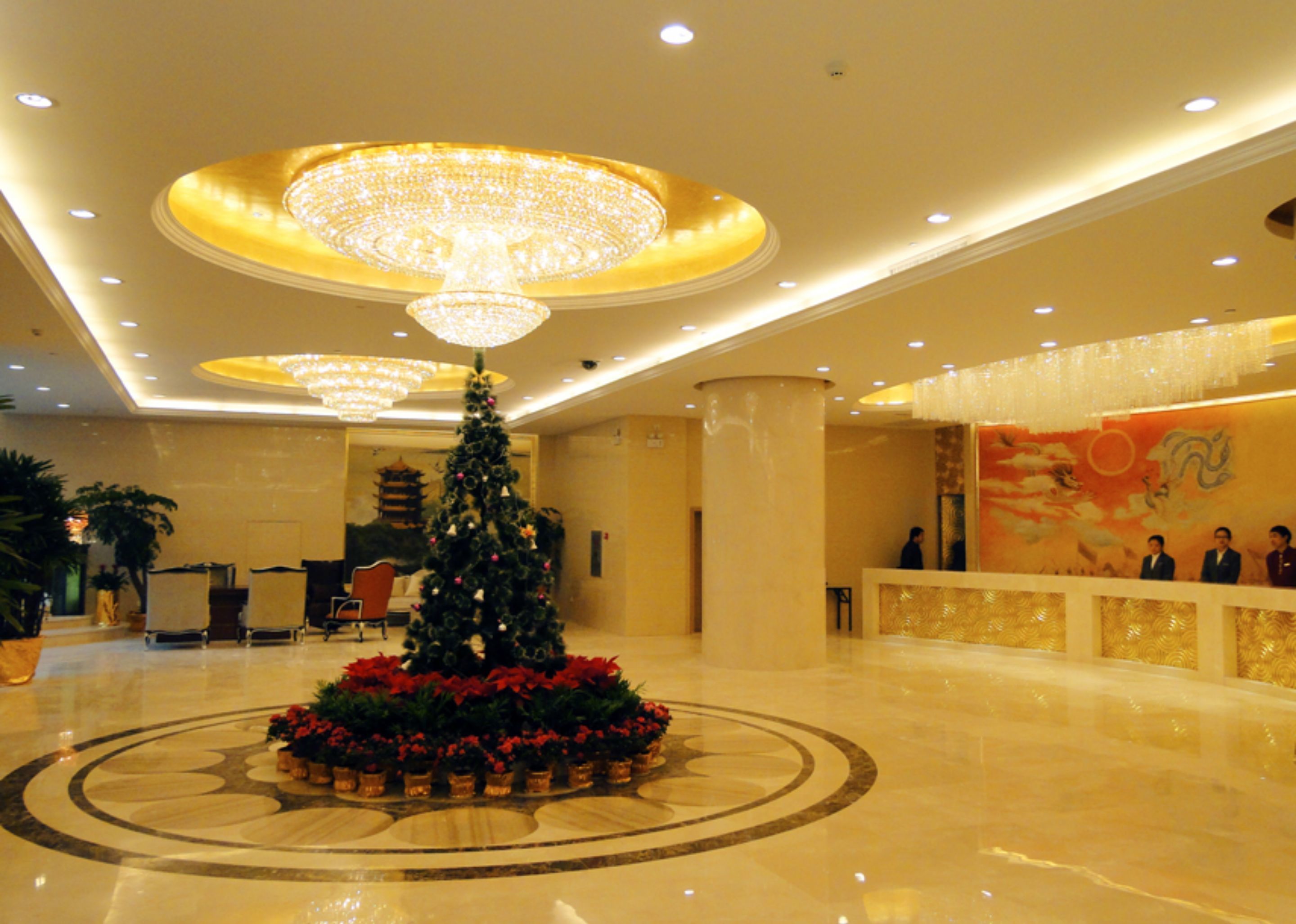 Un hall d’entrée décoré d’un sapin de Noël, de lustres et doté d’un comptoir d’accueil.