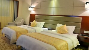 A hotel room with three beds, each with white bedding and yellow accents, a wooden headboard, and a nightstand with a lamp. - Wuhan Sentai Zhongyang Hotel (Wuhan)