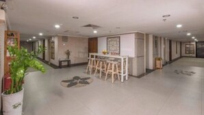 Eine geräumige Hotelhalle mit Bar im Zentrum, Sitzgelegenheiten und einer dekorativen Wand.