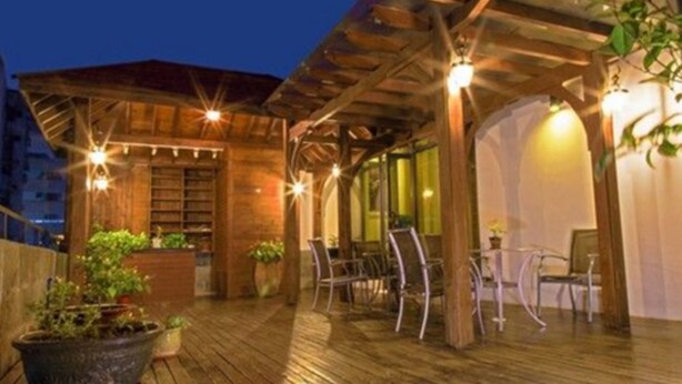 Eine Terrasse aus Holz mit Sitzgelegenheiten und Topfpflanzen, überdacht mit Lichterketten.