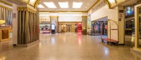 A spacious hotel lobby with a polished floor, a red telephone booth, and a seating area.