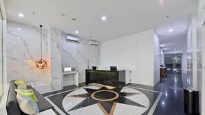 Un vestíbulo moderno con un mostrador de recepción, área de descanso y un diseño geométrico en el piso.