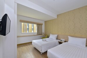 A hotel room with two beds, a TV, a window with curtains, and a wooden floor. - Whiz Hotel Falatehan Jakarta (Jakarta)