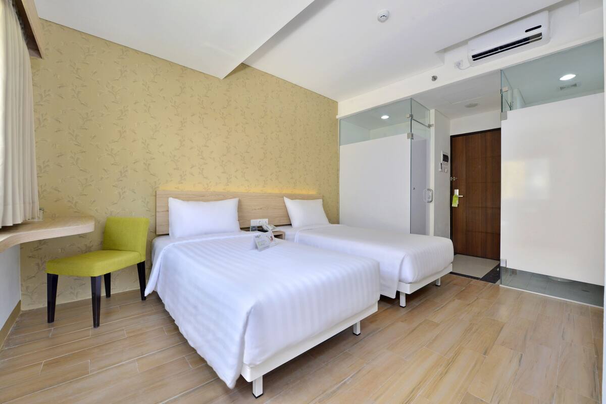 A hotel room with two beds, a desk, and a chair.