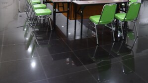 Un salón de conferencias con una larga mesa, sillas verdes y una pizarra.