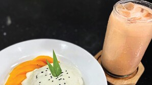 Un plato de arroz con mango y un vaso de té tailandés.