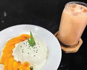 Un plato de arroz con mango y un vaso de té tailandés.