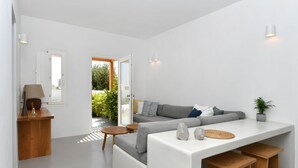 Een moderne woonkamer met een grijze bank, houten bijzettafeltjes en een witte salontafel.